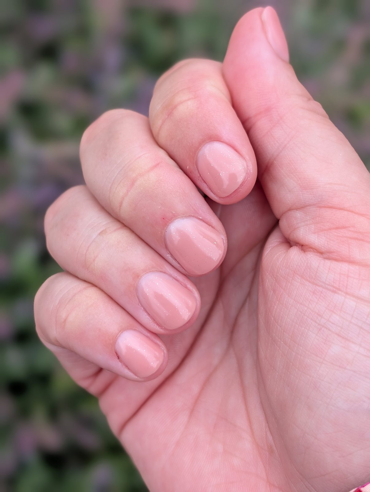 Roze glanzende nagels van dichtbij, in de tuin